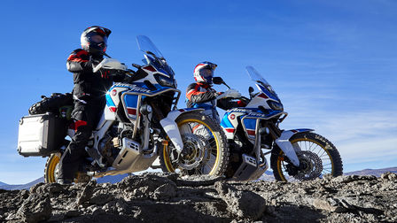 Deux pilotes sur les Honda Africa Twin Adventure Sports observant le paysage depuis une falaise.