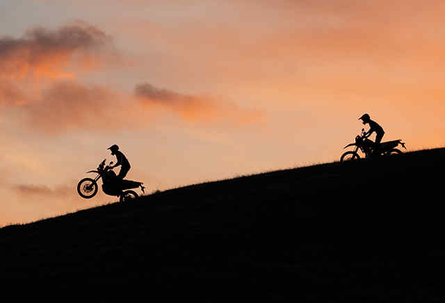 Deux motos Honda de la série 300 descendant une colline au coucher du soleil