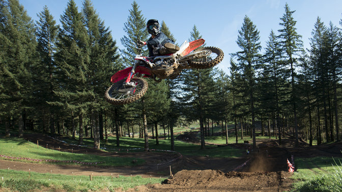 CRF450R avec pilote en plein saut. Chemin en terre.