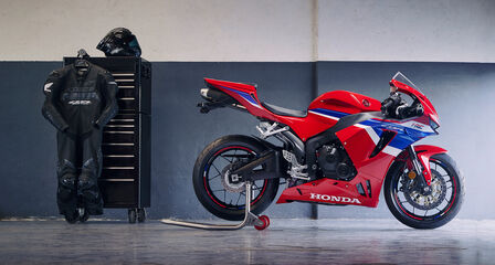 Honda CBR600RR parked in garage with race suit