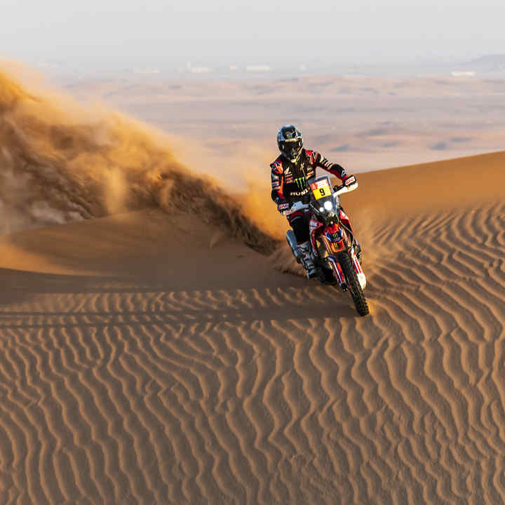 Pilote du Dakar sur une Honda dans les dunes du désert. 