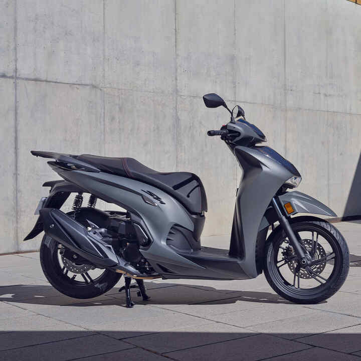 Deux Honda SH350i à l’arrêt à l'extérieur d'un bâtiment. 