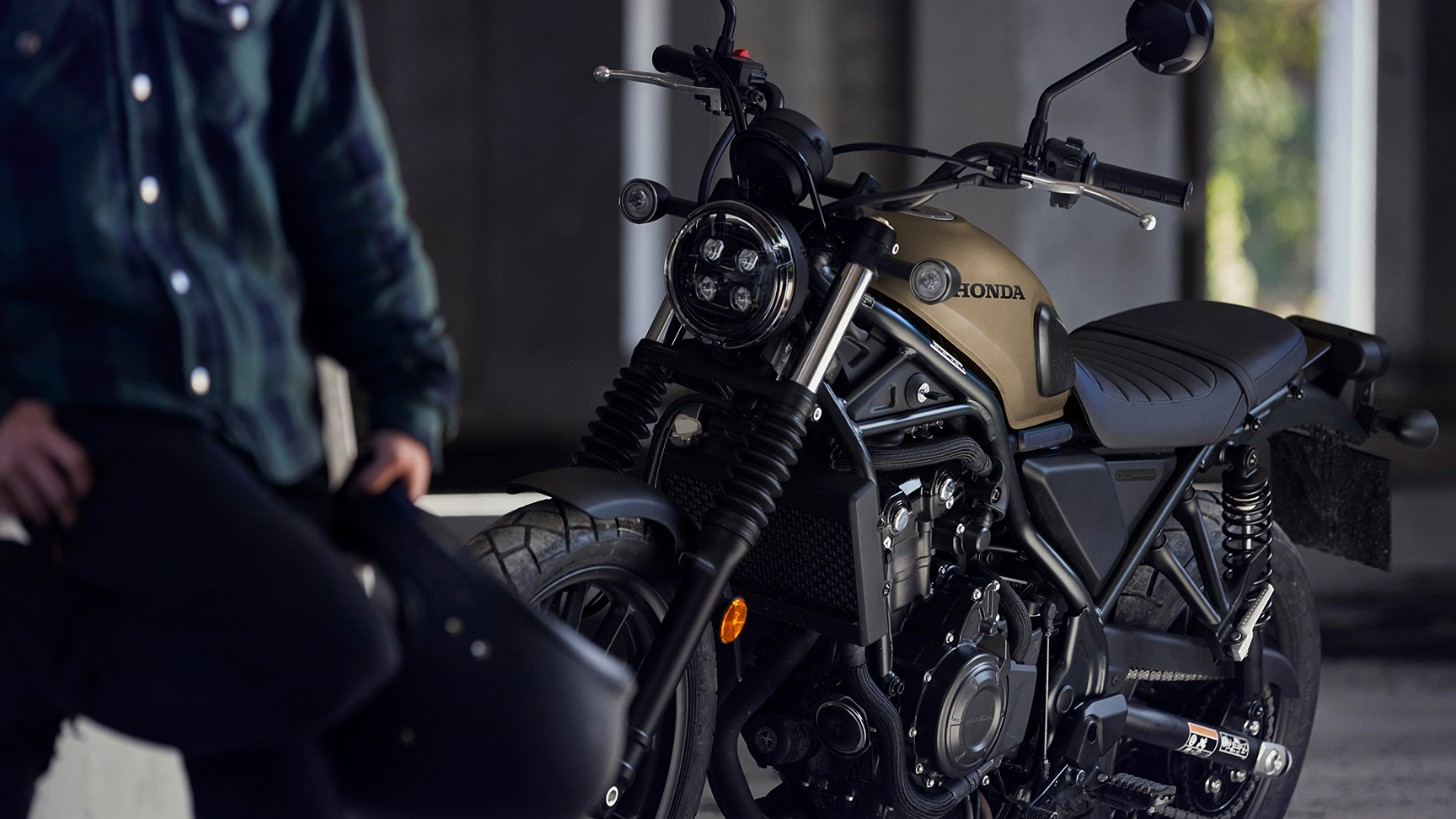 Mannequin debout à côté d'une moto CL500 dans un garage.